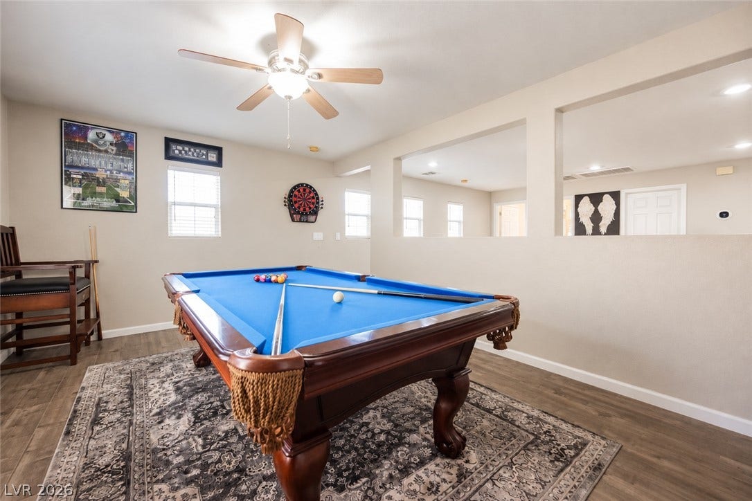 A spacious game room features hard surface flooring, recessed lighting, and partial partition walls.