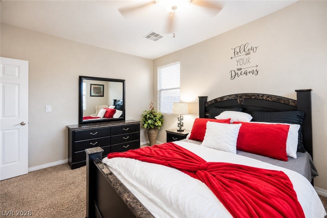 Plush carpeting anchors this comfortable bedroom suite under a tall ceiling.