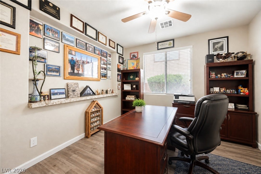 An inviting home office boasts rich wood flooring and a recessed display ledge.
