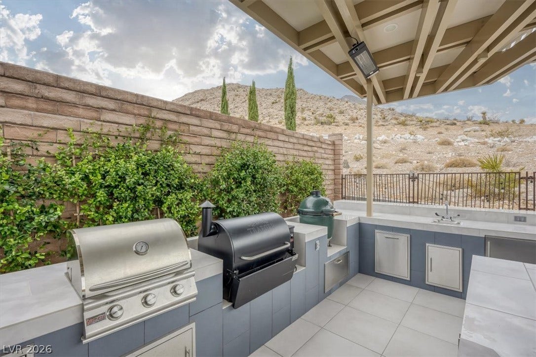 2611 Nevada Agave Lane, Las Vegas, NV 89138 A fully equipped outdoor kitchen stands under a covered patio against a scenic mountain backdrop.