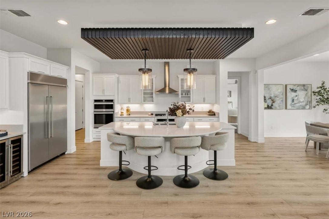 2611 Nevada Agave Lane, Las Vegas, NV 89138 Gleaming wood floors flow through this airy kitchen boasting a curved quartz island.