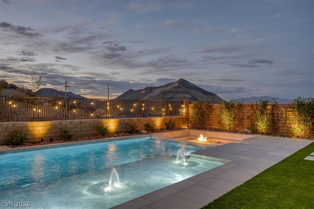 2611 Nevada Agave Lane, Las Vegas, NV 89138 An inviting swimming pool features integrated fountains and a fire pit against a mountain backdrop.