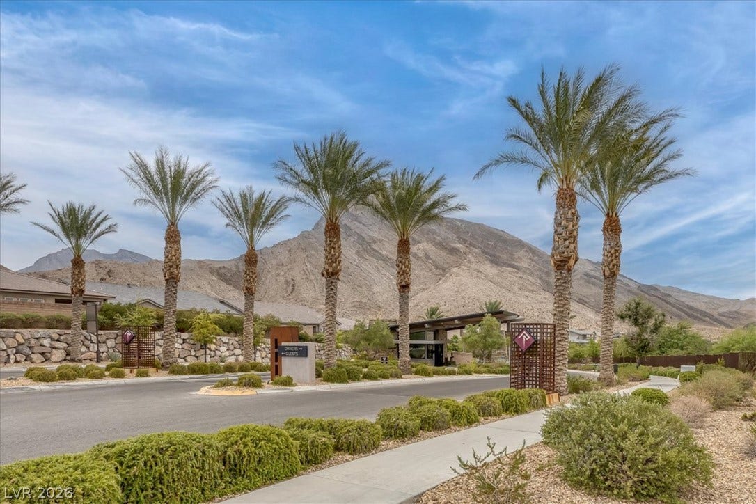 2611 Nevada Agave Lane, Las Vegas, NV 89138 An inviting gated entrance welcomes residents with mature palm trees set against majestic mountain views.
