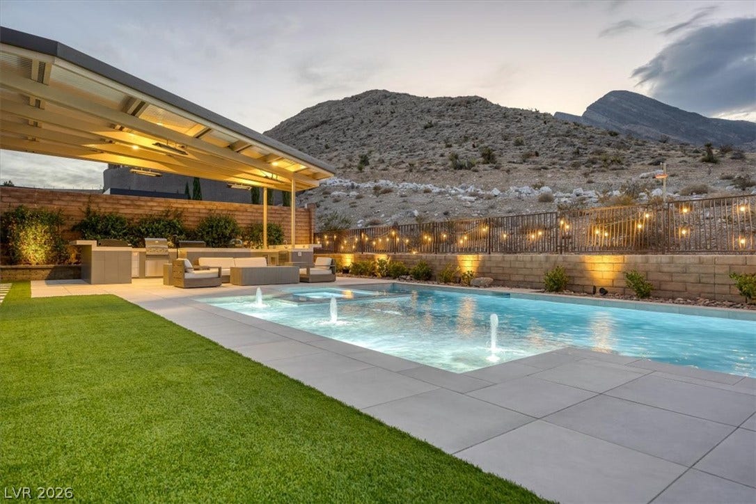 2611 Nevada Agave Lane, Las Vegas, NV 89138 Dramatic mountain backdrops frame a pristine pool complete with water fountains and modern patio tiling.