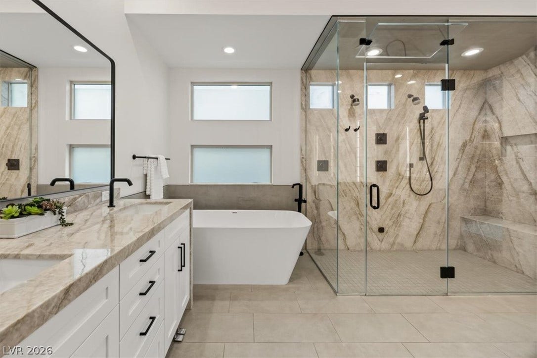 2611 Nevada Agave Lane, Las Vegas, NV 89138 A spacious bathroom features a stone-tiled shower, freestanding tub, and elegant stone counters.