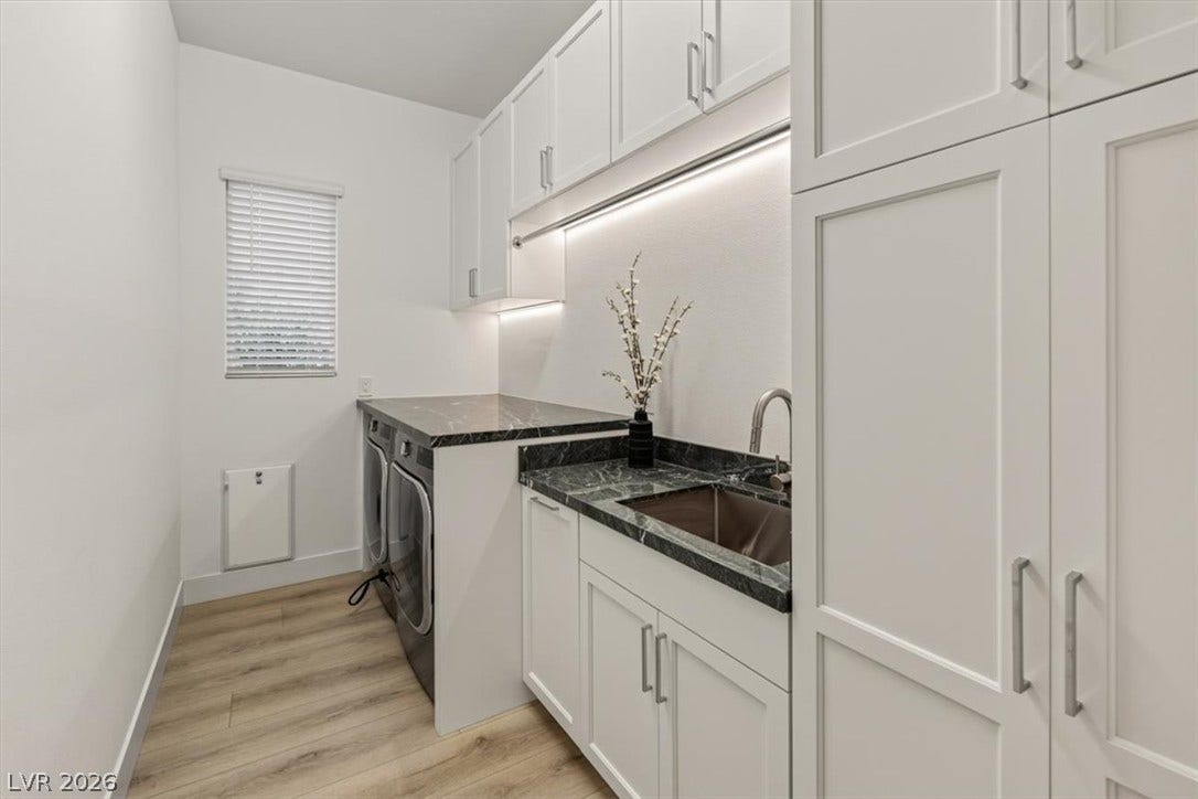 2611 Nevada Agave Lane, Las Vegas, NV 89138 Functional cabinetry and stone countertops elevate this modern laundry room with wood-texture flooring.
