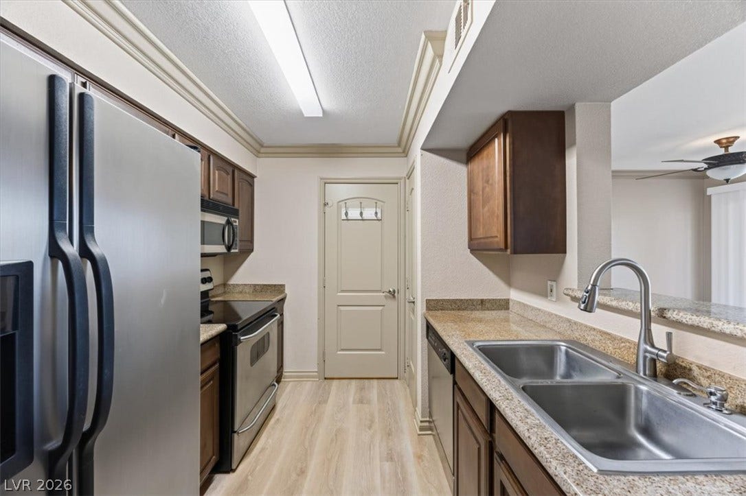 Rich wood cabinetry and stone countertops frame this functional galley kitchen layout.