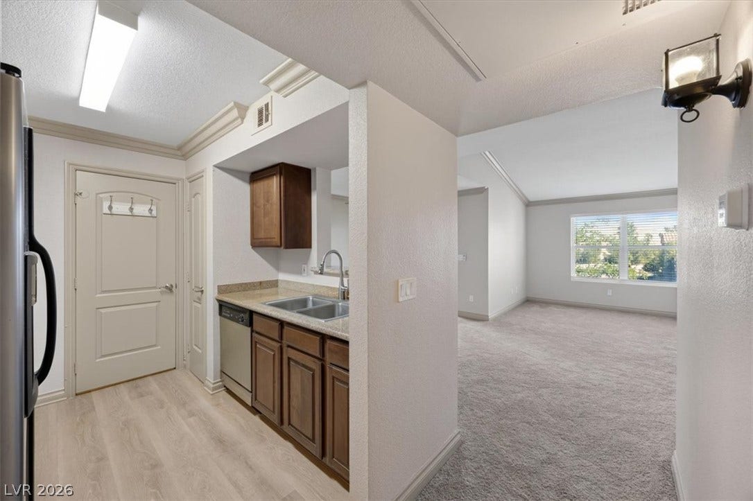 An open doorway links the functional kitchen space directly to a carpeted living area.