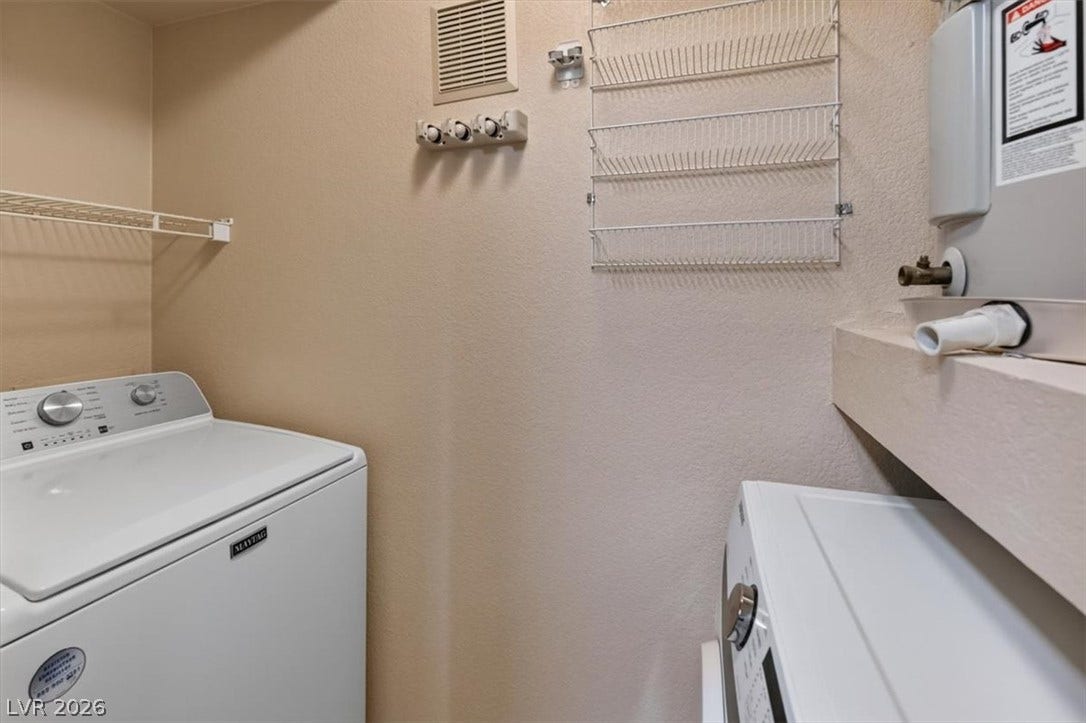 Functional utility space features dedicated laundry hookups and integrated storage shelving.
