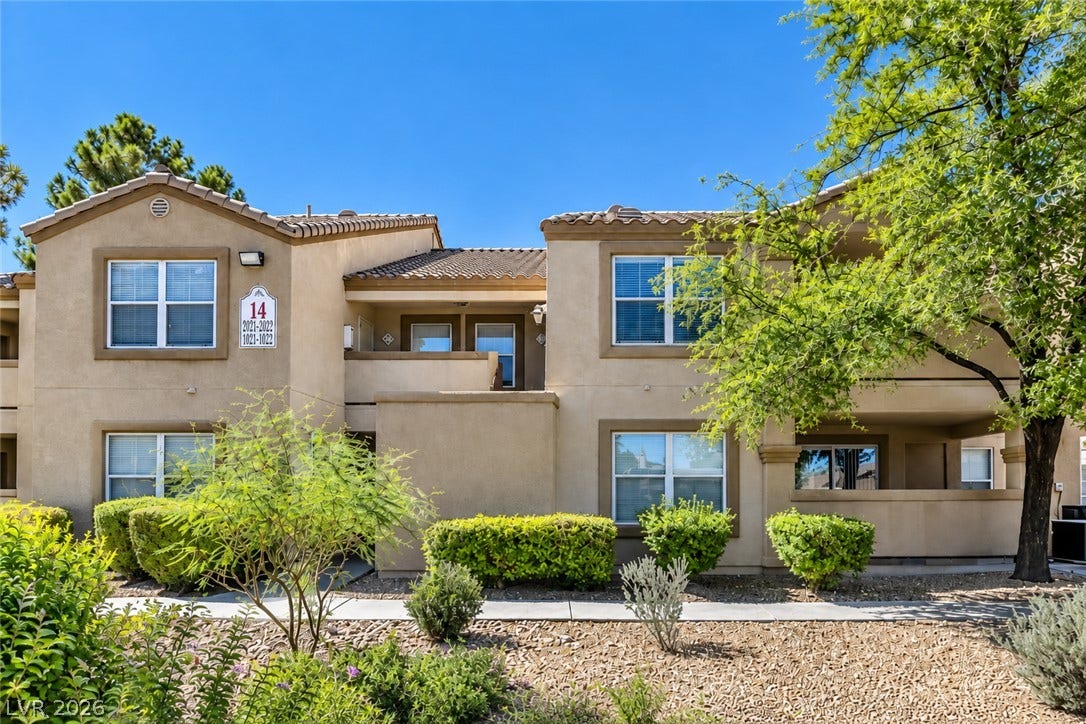 Mediterranean-inspired architecture highlights this multi-level exterior framed by mature trees and neat desert landscaping.