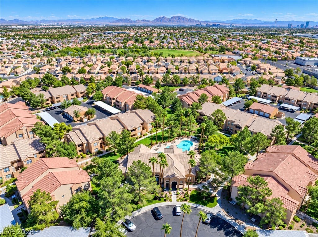 Distant mountains frame a sprawling community development centered around a resort-style swimming pool.
