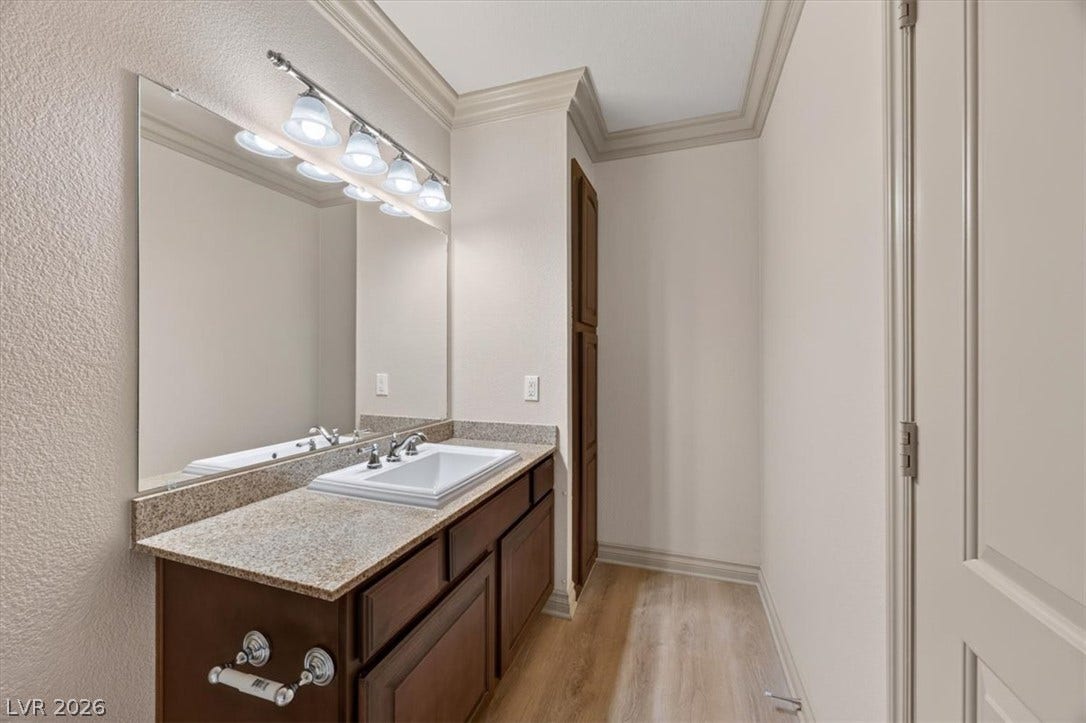Rich crown molding and granite countertops elevate this elegant washroom design.
