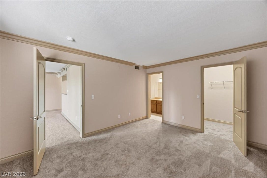 Crown molding and soft carpeting elevate this tranquil primary bedroom retreat.