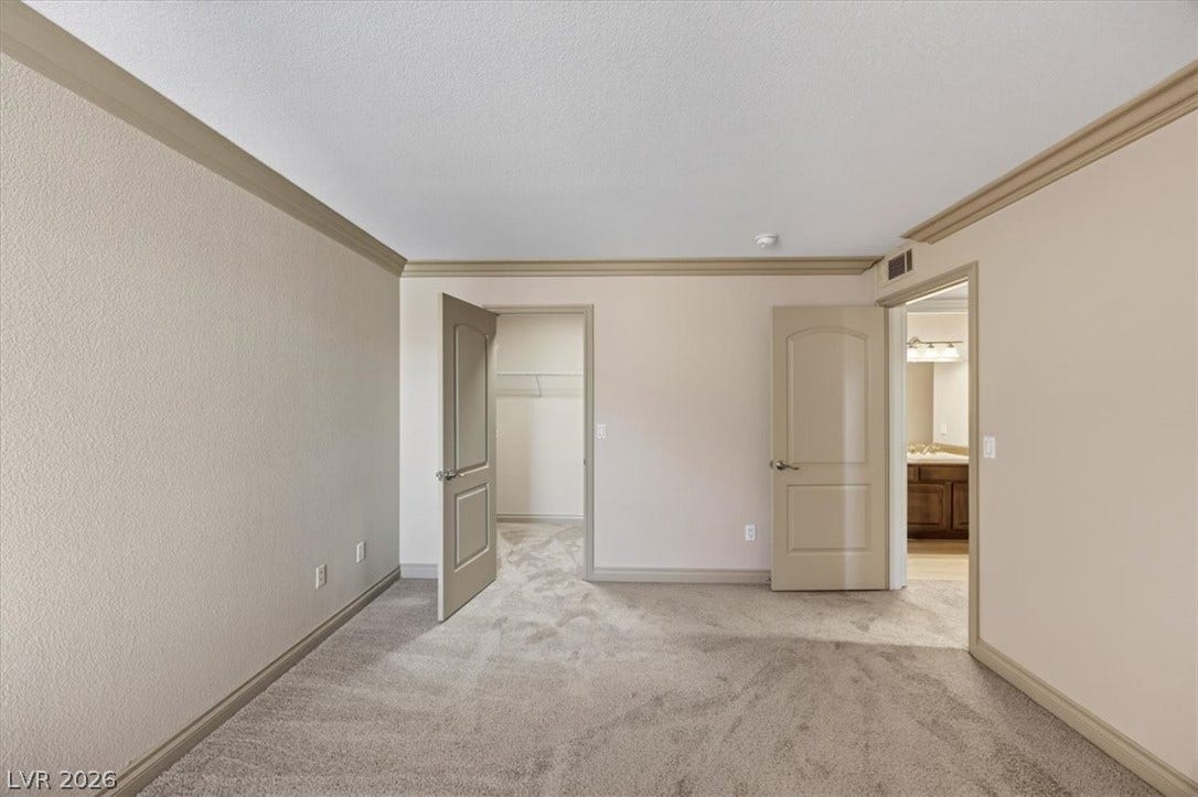 Elegant crown molding frames this comfortable bedroom space featuring plush carpeted floors.