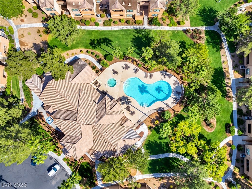 Lush manicured lawns and paved pathways surround a sparkling community pool and spa area.