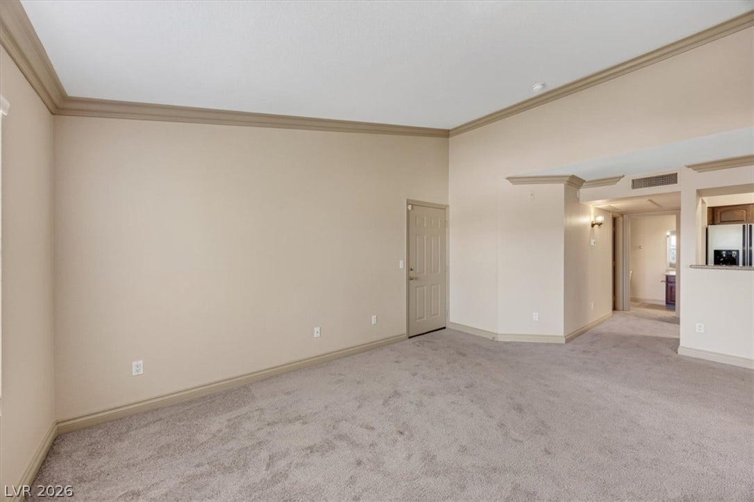 High ceilings and elegant crown molding define this open interior with soft plush carpeting.