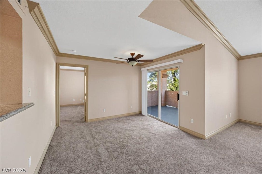 Sliding glass doors open to a private balcony, illuminating the carpeted interior with natural light.