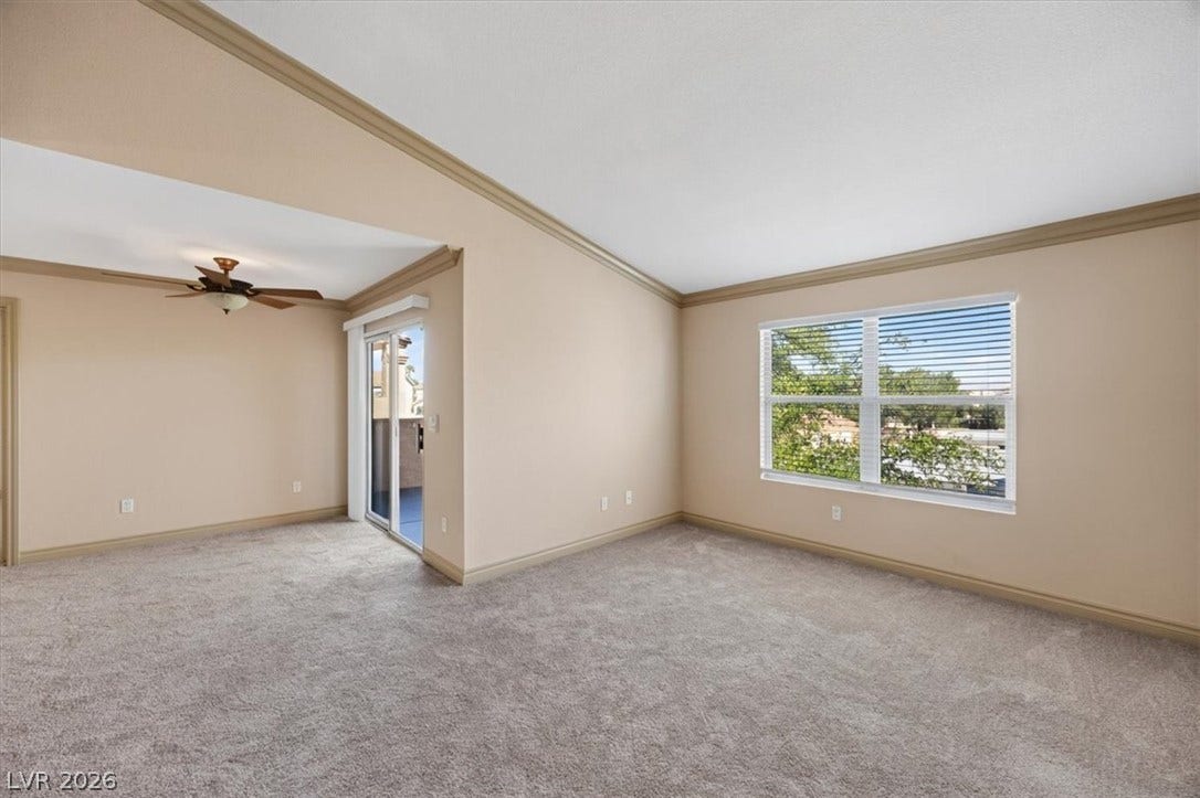 Vaulted ceilings and crown molding define this versatile living space featuring plush carpeting.