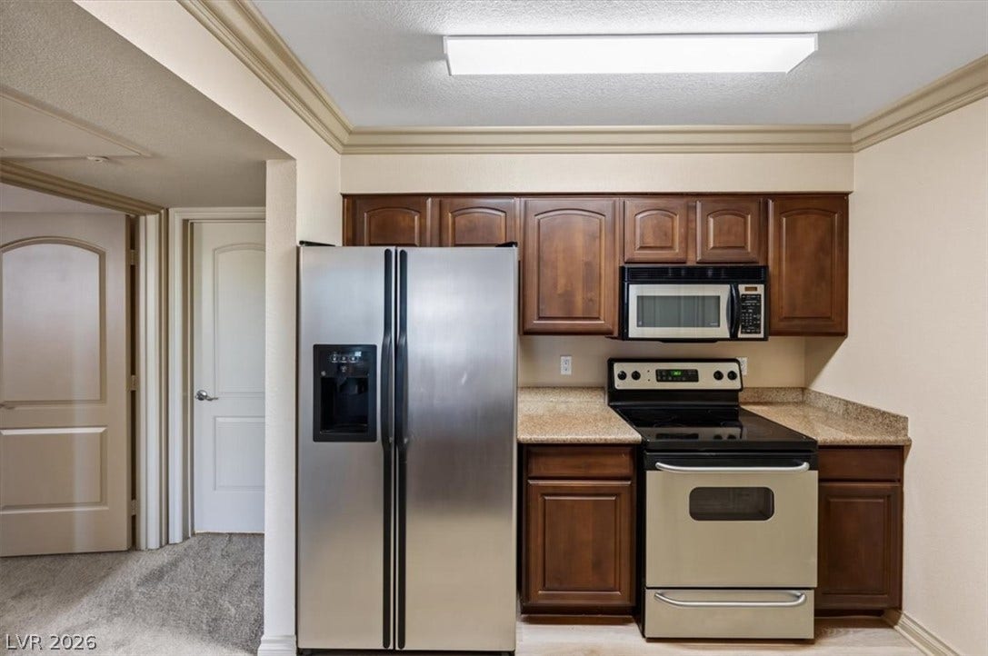 Rich wood cabinetry and stone countertops anchor this functional cooking space.