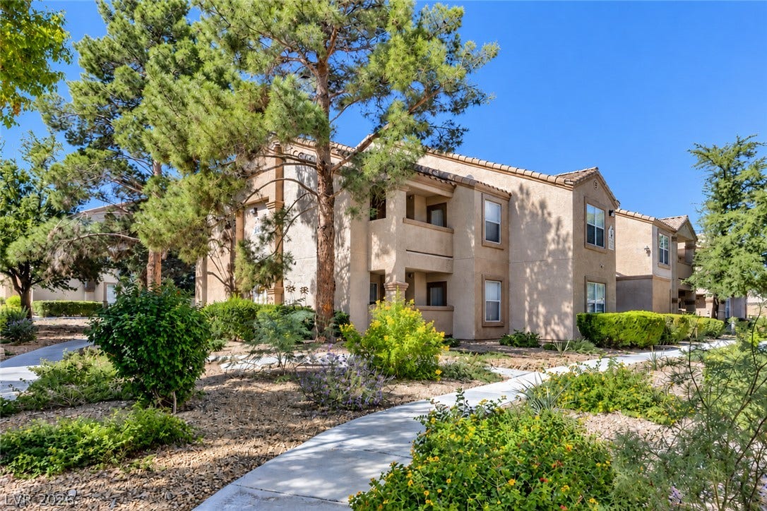 Stucco exteriors and tiled roofs define this multi-level residential building nestled among mature trees.