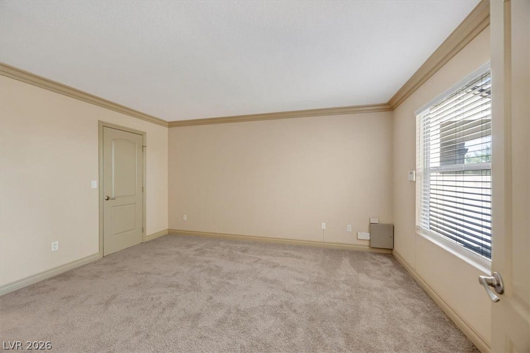 Plush carpeting and elegant crown molding define this versatile bedroom space.