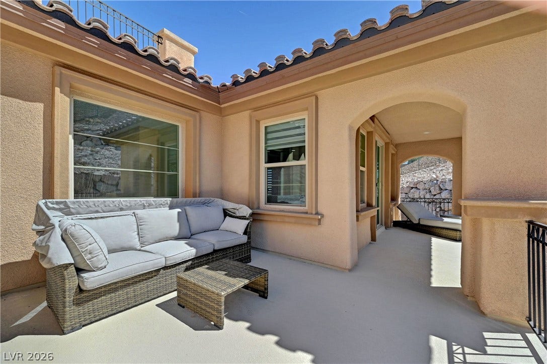 89 Olympia Chase Drive, Las Vegas, NV 89141 Stucco walls and Spanish tile rooflines frame this secluded courtyard terrace under open skies.