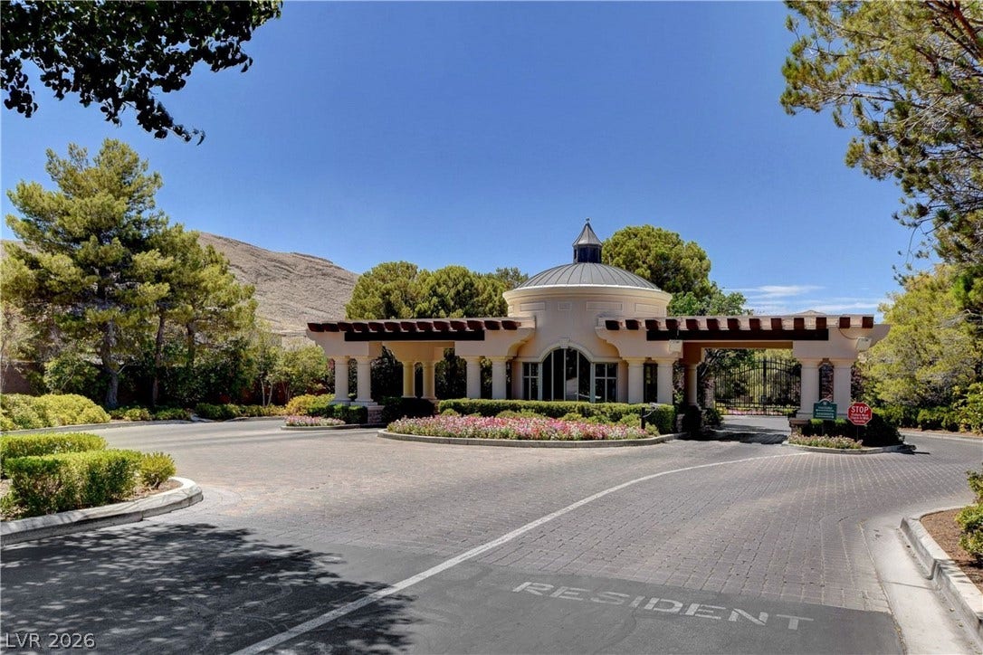 89 Olympia Chase Drive, Las Vegas, NV 89141 An elegant gated entry structure anchors the manicured grounds under clear blue skies.