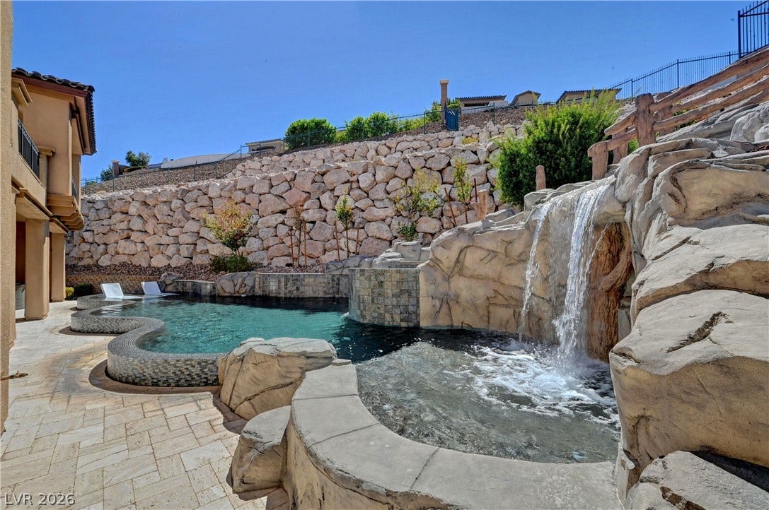 89 Olympia Chase Drive, Las Vegas, NV 89141 An inviting backyard oasis features a rock waterfall and stone patio surroundings.