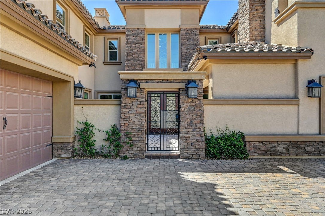 89 Olympia Chase Drive, Las Vegas, NV 89141 An elegant gated courtyard entry matches the stone accents and tiled rooflines of this residence.