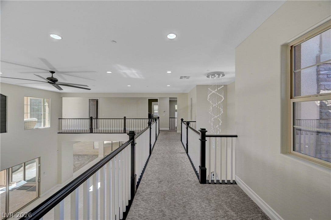 89 Olympia Chase Drive, Las Vegas, NV 89141 An upper-level catwalk overlooking the main living areas below features neutral carpeting and recessed lighting.