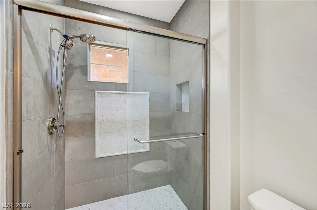 89 Olympia Chase Drive, Las Vegas, NV 89141 Sleek tile surrounds and a glass enclosure define this modern walk-in shower design.