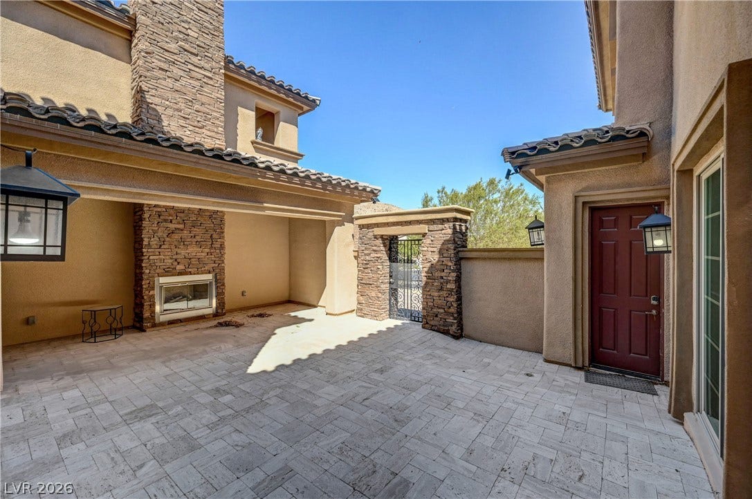 89 Olympia Chase Drive, Las Vegas, NV 89141 An inviting stone-paved courtyard is anchored by a handsome outdoor fireplace under open blue skies.