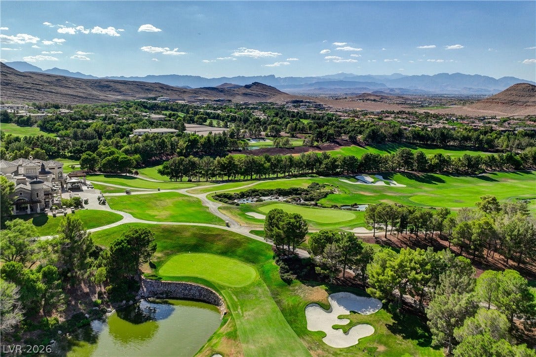 89 Olympia Chase Drive, Las Vegas, NV 89141 Rolling fairways and a serene water hazard frame majestic mountain backdrops under clear blue skies.
