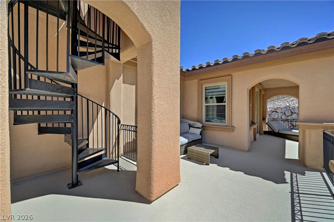 89 Olympia Chase Drive, Las Vegas, NV 89141 An outdoor spiral staircase leads to an upper level from this spacious stucco balcony.