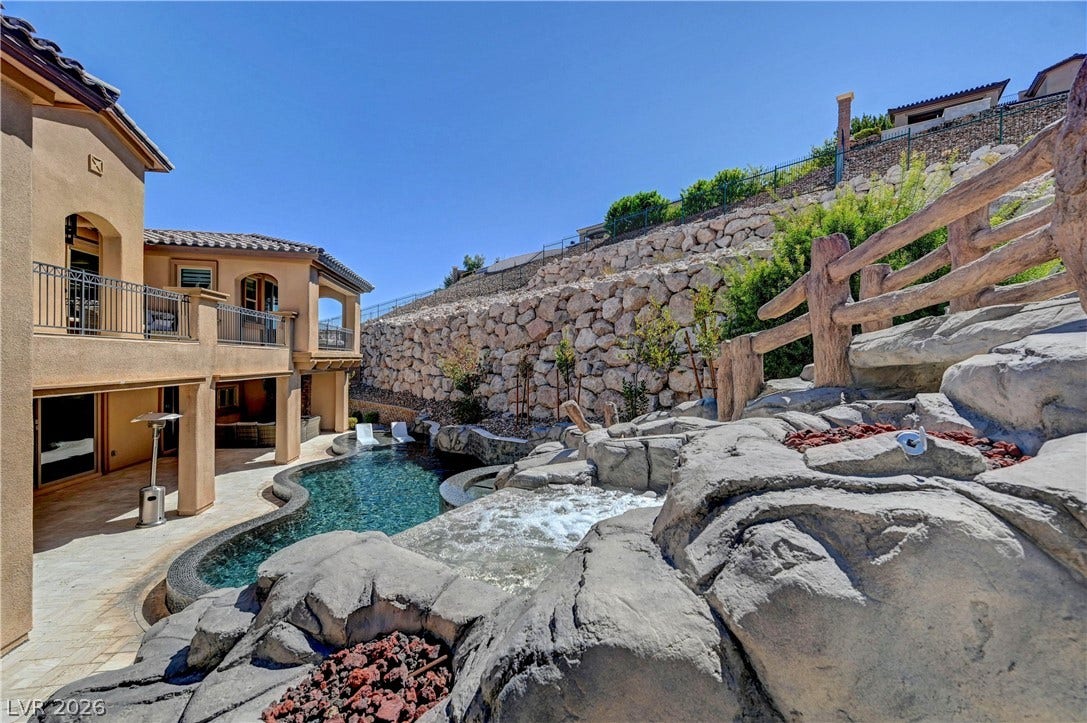 89 Olympia Chase Drive, Las Vegas, NV 89141 Dramatic rock formations and a tiered waterfall feature overlook a custom swimming pool.