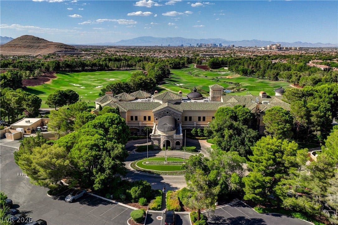 89 Olympia Chase Drive, Las Vegas, NV 89141 An aerial perspective showcases a grand stone estate bordering an expansive golf course green.