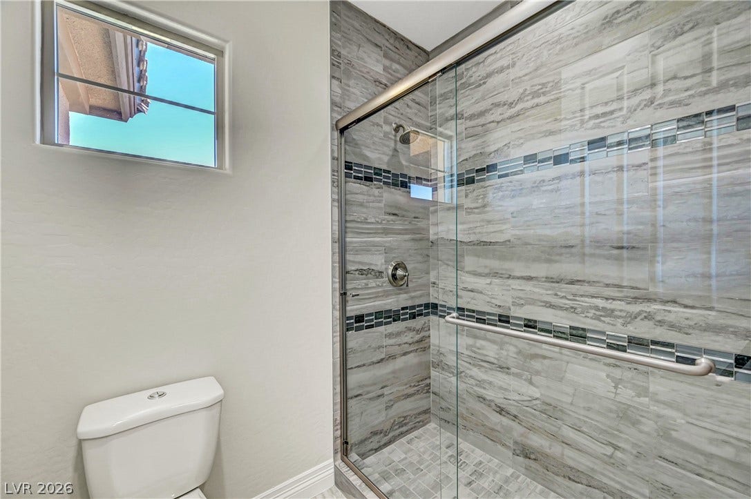 89 Olympia Chase Drive, Las Vegas, NV 89141 Custom wall tile and a sleek glass enclosure define this modern walk-in shower.
