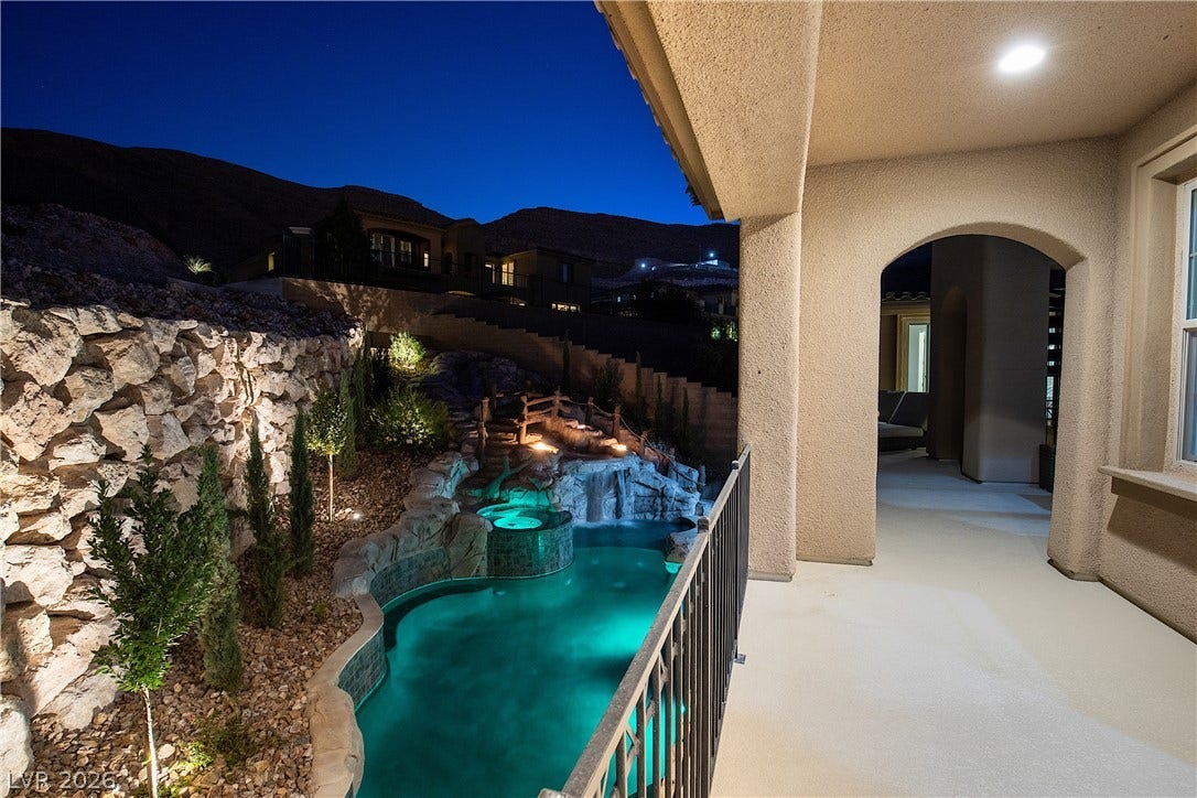 89 Olympia Chase Drive, Las Vegas, NV 89141 An arched patio overlooks a custom pool and spa set against a rocky hillside backdrop.