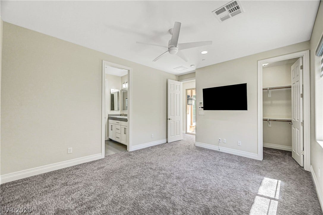 89 Olympia Chase Drive, Las Vegas, NV 89141 Plush carpeting anchors this spacious bedroom featuring an attached bath and a walk-in closet.