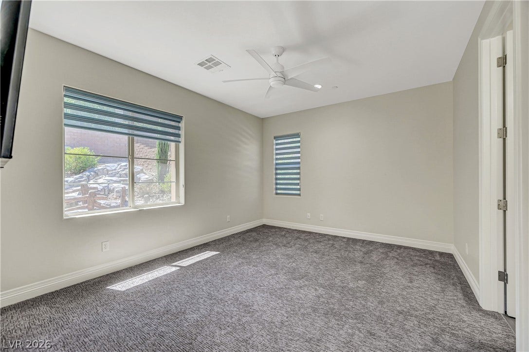 89 Olympia Chase Drive, Las Vegas, NV 89141 Plush carpeting and dual windows illuminate this serene secondary bedroom space.