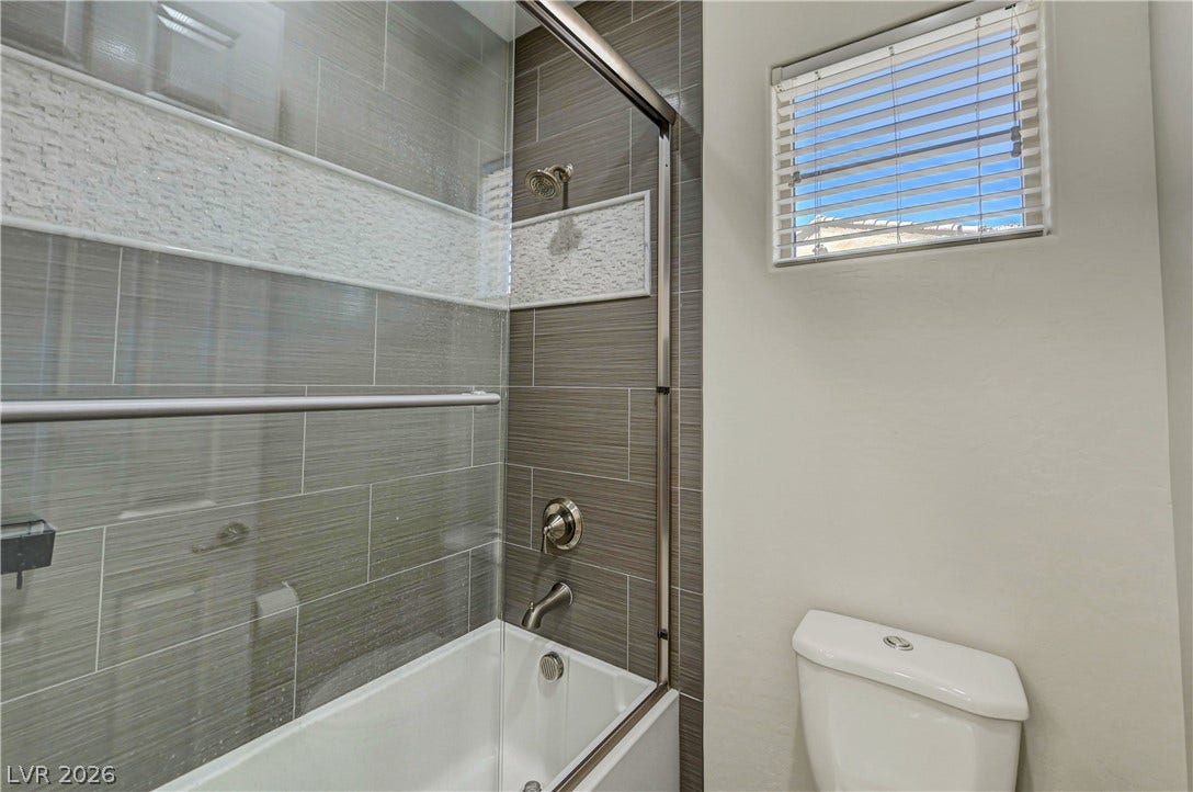89 Olympia Chase Drive, Las Vegas, NV 89141 Modern wall tile and glass doors elevate this bright bathroom space.