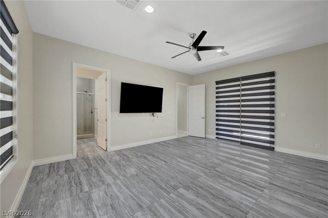 89 Olympia Chase Drive, Las Vegas, NV 89141 Polished tile flooring anchors this modern room showcasing an attached bath and sliding doors.