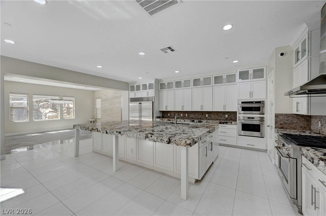 89 Olympia Chase Drive, Las Vegas, NV 89141 Polished tile flooring and an expansive stone island anchor this light-filled gourmet space.