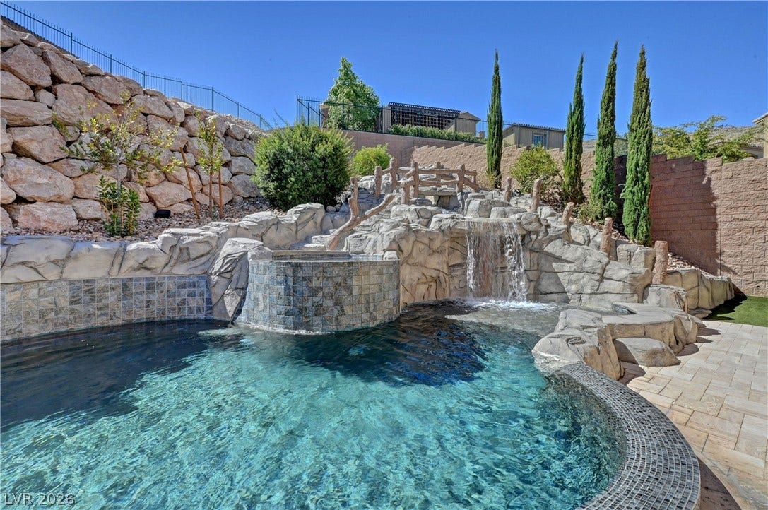 89 Olympia Chase Drive, Las Vegas, NV 89141 An oasis backyard boasts a custom swimming pool detailed with natural rock and waterfalls.