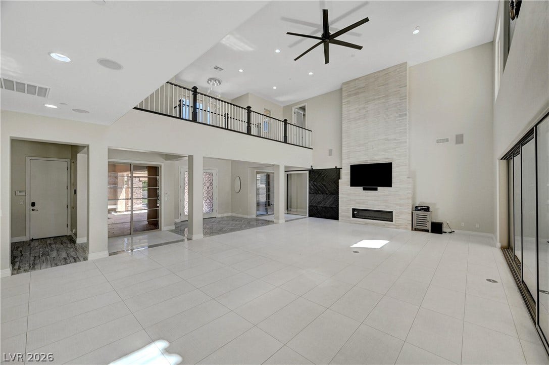 89 Olympia Chase Drive, Las Vegas, NV 89141 Towering ceilings and a modern tile fireplace anchor this grand, open-concept living space.
