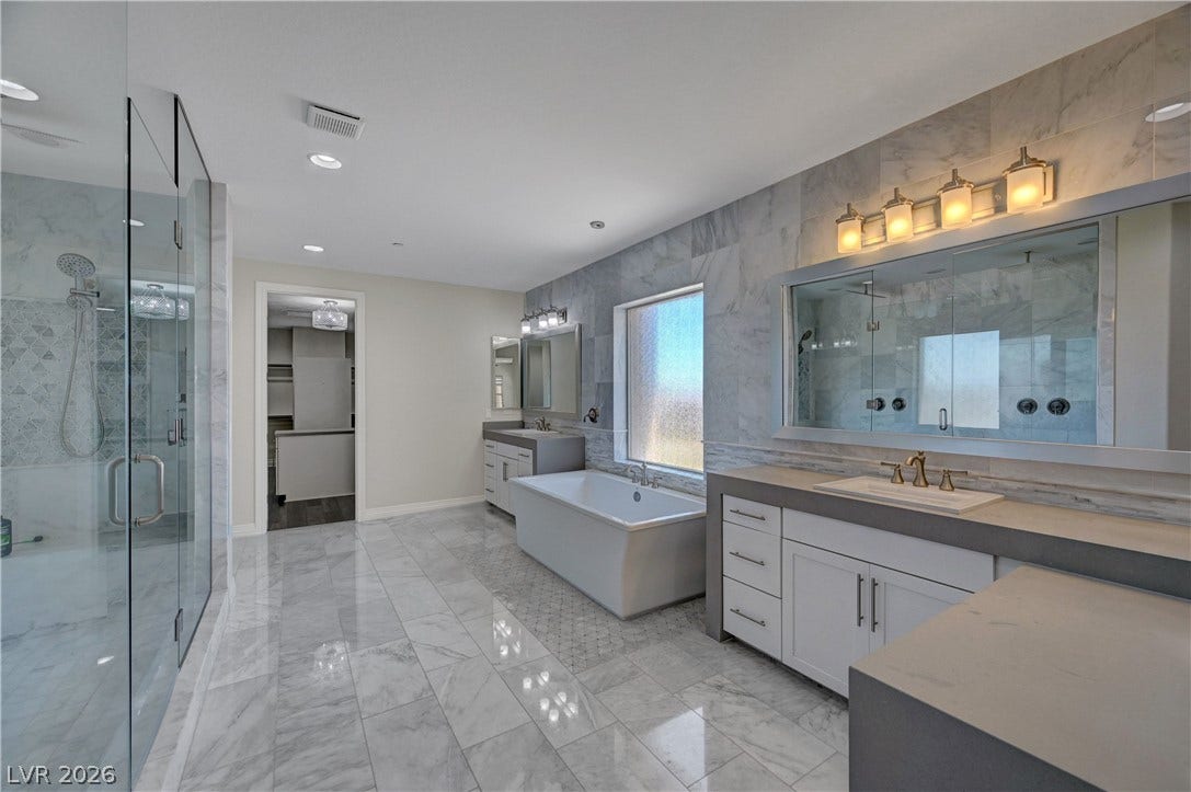 89 Olympia Chase Drive, Las Vegas, NV 89141 Gleaming marble floors and a freestanding tub highlight this modern, spa-like bathroom.