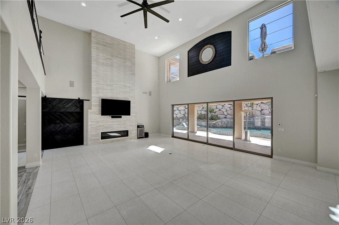 89 Olympia Chase Drive, Las Vegas, NV 89141 Soaring ceilings and a floor-to-ceiling fireplace anchor this grand tiled living room.