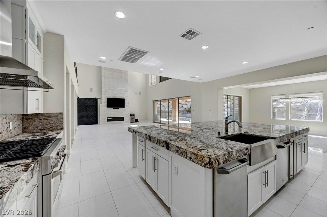 89 Olympia Chase Drive, Las Vegas, NV 89141 Gleaming stone countertops and a spacious island anchor this expansive, light-filled culinary space.