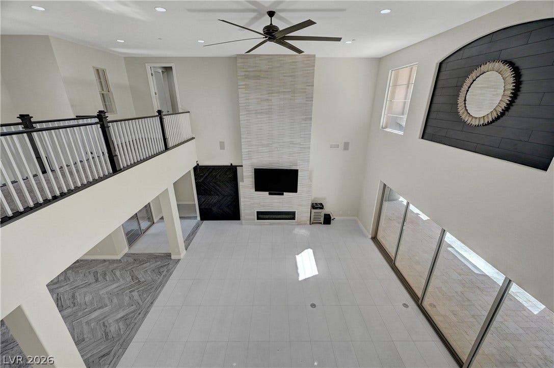 89 Olympia Chase Drive, Las Vegas, NV 89141 Soaring ceilings and a towering fireplace highlight this expansive multi-level living area.