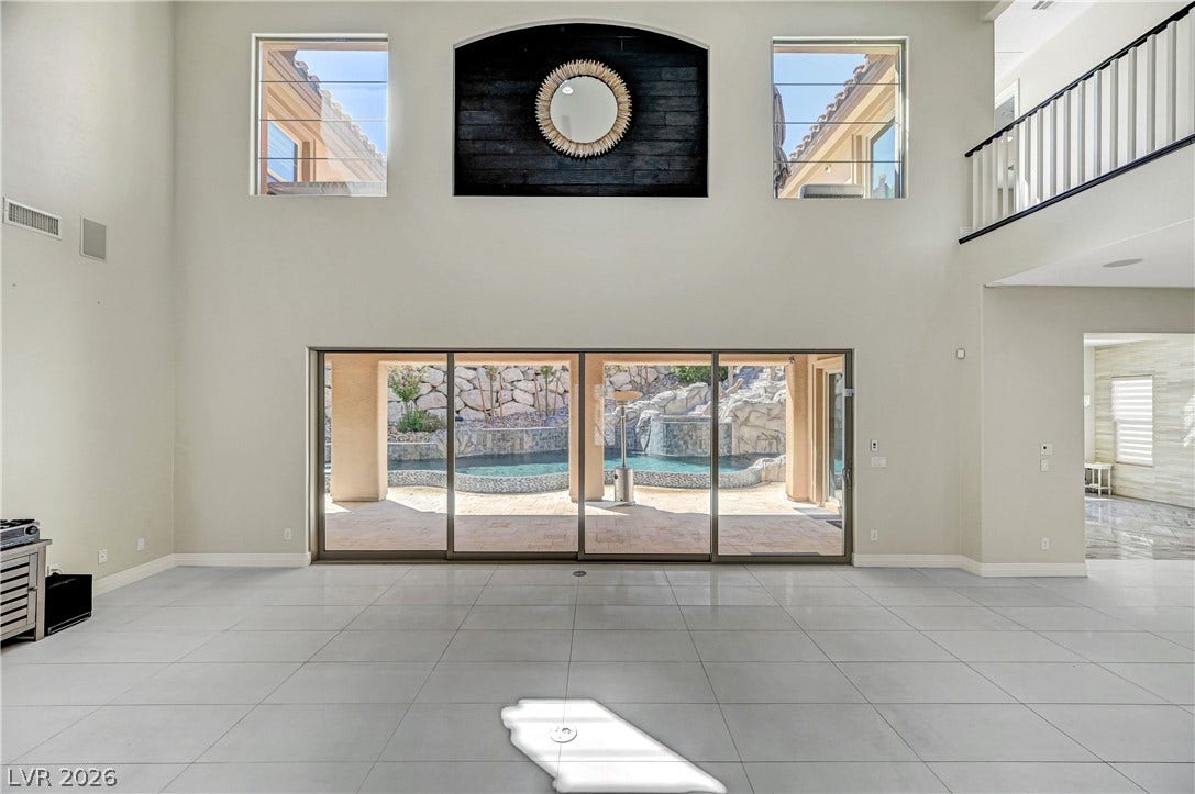89 Olympia Chase Drive, Las Vegas, NV 89141 Massive sliding glass doors reveal a private pool area from this spacious, tiled living room.